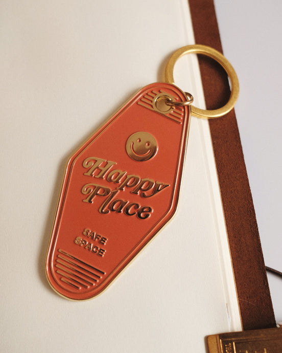 Orange keychain tag with 'Happy Place' text and smiley face on a white background